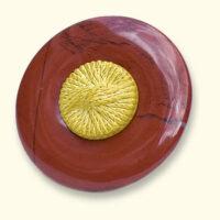A jasper Mourning Button with a yellow button from a beloved one on it. The red jasper is often veined.