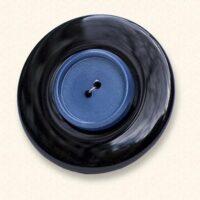 An onyx Mourning Button with a blue button of a loved one on it. The black onyx is always evenly coloured.