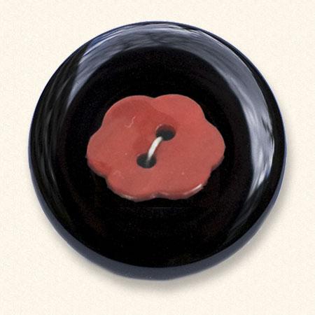 An onyx Mourning Button with a red fabric button of a loved one on it. The black onyx is always evenly coloured.